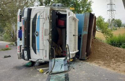 रेत से लदा एक टिप्पर अनियंत्रित होकर सड़क किनारे पल्टा